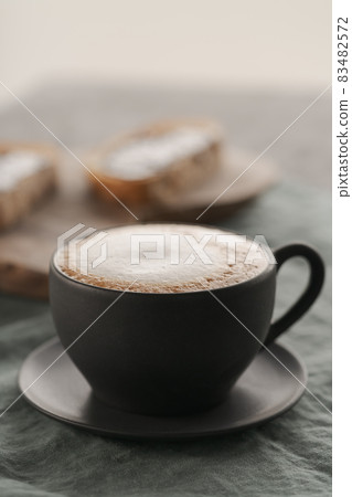 Cappuccino in black cup with ciabatta slices with chocolate spread on background 83482572