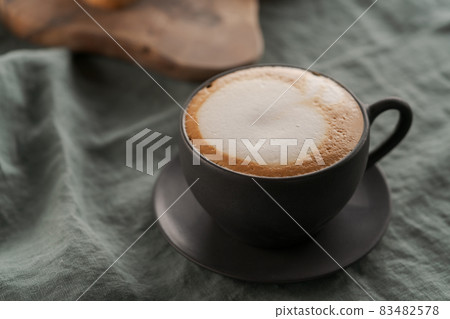 Cappuccino in black cup with ciabatta slices with chocolate spread on background Cappuccino in black cup with ciabatta slices with chocolate spread on background 83482578