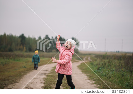 Little caucasian girl running in the field with her brother making funny faces Little caucasian girl running in the field with her brother making funny faces 83482894
