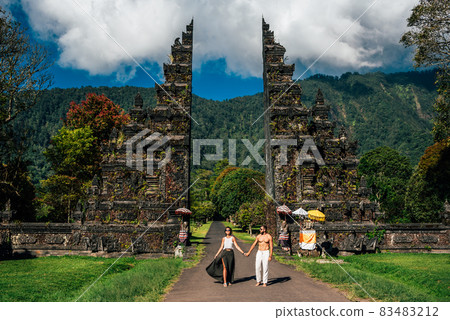 Beautiful couple at the Bali temple. Man and woman traveling in Indonesia. Couple at the Bali gate. The couple travels the world. Tourists in Bali. Travel to tourist places in Asia. Copy space Beautiful couple at the Bali temple. Man and woman traveling in Indonesia. Couple at the Bali gate. The couple travels the world. Tourists in Bali. Travel to tourist places in Asia. Copy space 83483212