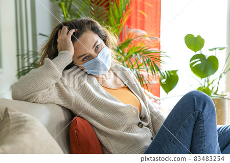 Sad young woman isolated stay at home in protective sterile mask on her face 83483254