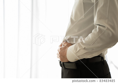 A man in a suit is putting his hand on his abdomen A man in a suit is putting his hand on his abdomen 83483485