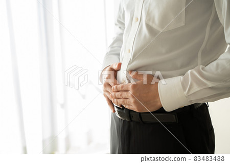 A man in a suit is putting his hand on his abdomen 83483488