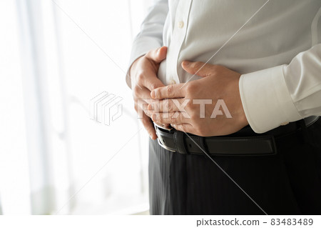A man in a suit is putting his hand on his abdomen 83483489