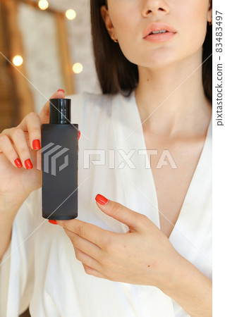 Beautiful fresh young woman applying cream or body wash on hand from dispenser indoors Beautiful fresh young woman applying cream or body wash on hand from dispenser indoors 83483497