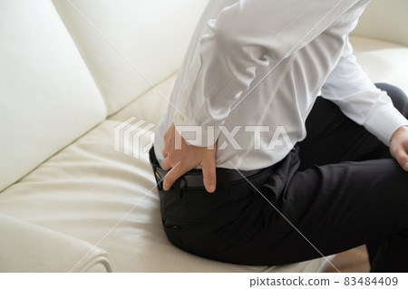 A businessman sitting on the sofa and hurt his back A businessman sitting on the sofa and hurt his back 83484409
