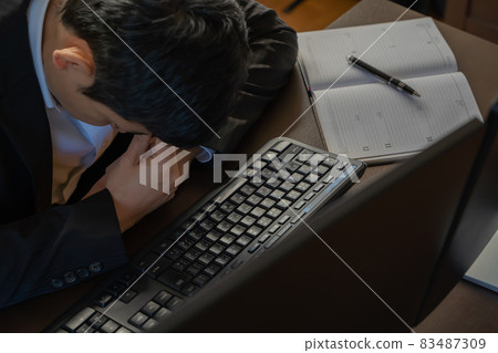 一個男人在電腦前握著內眼角的身影 83487309