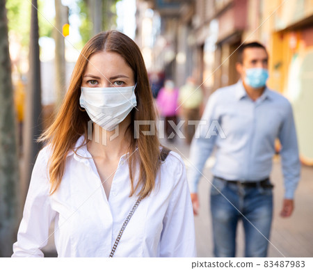 Woman wearing disposable face mask walking on street Woman wearing disposable face mask walking on street 83487983