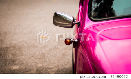 Side mirror and window of beautiful vintage pink car over blur background 83490032