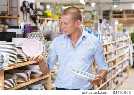 Attentive man choosing new crockery in dinnerware store closeup Attentive man choosing new crockery in dinnerware store closeup 83491966