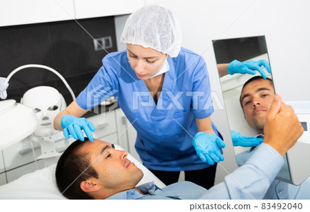 Woman beautician consulting male client before facial treatment Woman beautician consulting male client before facial treatment 83492040