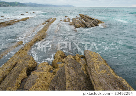Atlantic ocean coast at low tide in Bay of Biscay. Charming Zumaia Itzurun beach. K-T boundary. Mid-cretaceous period. For  greeting card design, postcard template, touristic guide, magazine, poster. 83492294