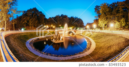 Gomel, Homiel, Belarus. Panorama Of Park Watercourse Channel Flowing Into River Through Stone Bridge In City Park In Evening Or Night Illumination Gomel, Homiel, Belarus. Panorama Of Park Watercourse Channel Flowing Into River Through Stone Bridge In City Park In Evening Or Night Illumination 83493523