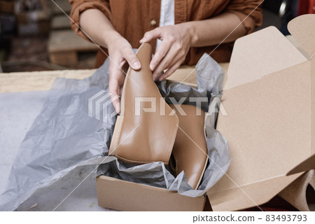 Close-up of woman packing new pair of shoes into box for delivering 83493793