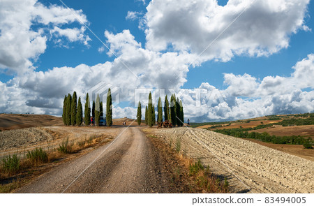 San Quirico d'Orcia, Tuscany, Italy. August 2020. The circular grove of cypresses is a symbol of the landscapes of Tuscany, presence of tourists. San Quirico d'Orcia, Tuscany, Italy. August 2020. The circular grove of cypresses is a symbol of the landscapes of Tuscany, presence of tourists. 83494005