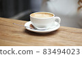 Side view of white cup of black coffe on light wooden table background. Media. Closeup shot of cup of coffee. 83494023