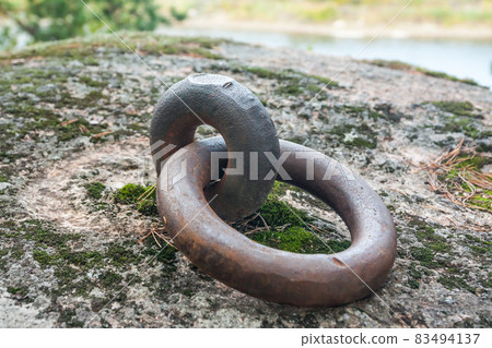 Closeup of a rusty old mooring loop fastened in a rock, used to tie up boats in the river Closeup of a rusty old mooring loop fastened in a rock, used to tie up boats in the river 83494137