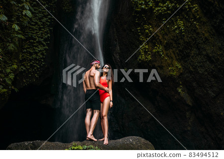 Beautiful couple at a waterfall in Indonesia. Honeymoon trip. Happy couple on the island of Bali. Beautiful couple travels the world. Travel to Indonesia. Happy couple on vacation. Copy space. 83494512