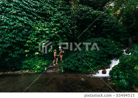 A couple in love at a waterfall in Indonesia. A couple in love in the tropics. Beautiful couple traveling on the island of Bali. Man and woman on the background of nature. Copy space 83494515