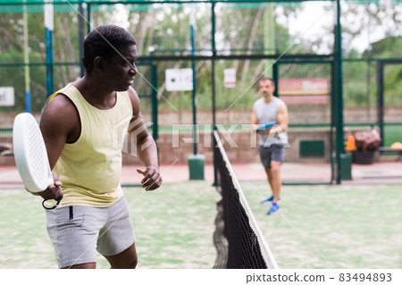 African american man and his partner playing paddle tennis on padel court African american man and his partner playing paddle tennis on padel court 83494893