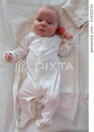 baby girl holding toy in hand, playing with wooden beanbag 83495014