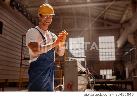 Cheerful builder using woodworking machine in workshop Cheerful builder using woodworking machine in workshop 83495046