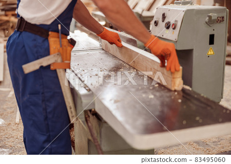 Male carpenter using woodworking machine in workshop 83495060