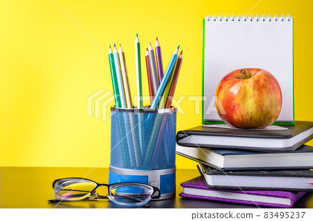 Back to school concept. School supplies, apple and books on a yellow background. Place for text. Back to school concept. School supplies, apple and books on a yellow background. Place for text. 83495237