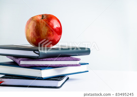 Books and apple on a white background. Back to school concept. Place for text. Books and apple on a white background. Back to school concept. Place for text. 83495245