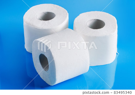 Three rolls of toilet paper on a blue background. Panic purchase of essential goods. The coronavirus epidemic in the world. 83495340