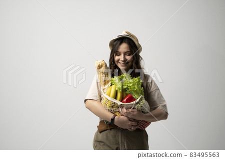 Portrait of young woman with a eco bag of vegetables, greens. Sustainable lifestyle. Eco friendly concept. 83495563