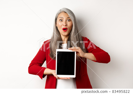 Business. Surprised and happy asian female entrepreneur showing promotion on blank digital tablet screen, staring at camera amazed, white background Business. Surprised and happy asian female entrepreneur showing promotion on blank digital tablet screen, staring at camera amazed, white background 83495822