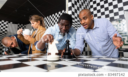 Group of friends solving puzzle together in quest room stylized chessboard Group of friends solving puzzle together in quest room stylized chessboard 83497142