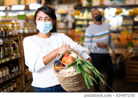 Woman in medical mask with purchases in supermarket Woman in medical mask with purchases in supermarket 83497150
