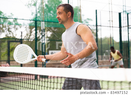 Young adult men playing doubles paddle tennis Young adult men playing doubles paddle tennis 83497152