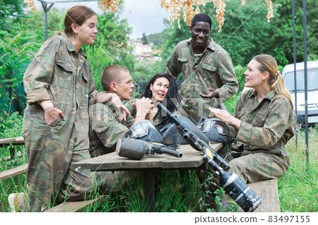 Smiling friends chatting after successful paintball match Smiling friends chatting after successful paintball match 83497155