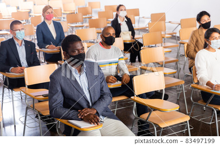 People in protective masks sitting in conference room during business training People in protective masks sitting in conference room during business training 83497199