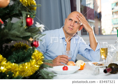 Lonely man drinking alcohol at the christmas table Lonely man drinking alcohol at the christmas table 83497321