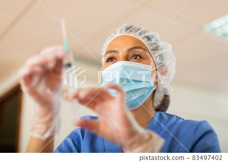 Female nurse in mask holding syringe for injection 83497402