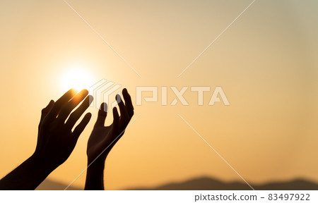 Closeup woman hands praying for blessing from god during sunset background. Hope and freedom concept. Closeup woman hands praying for blessing from god during sunset background. Hope and freedom concept. 83497922