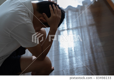 A man sitting on the sofa and holding his head 83498133