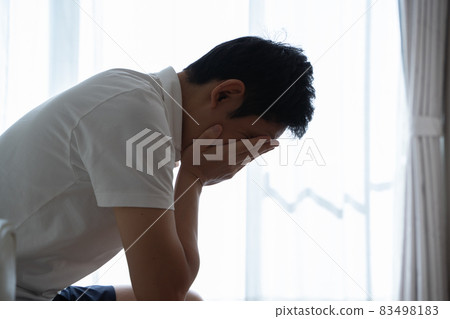 一個人坐在沙發上，抱著頭 83498183