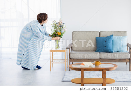 A woman decorating a flower in the living room 83501202