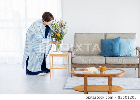 A woman decorating a flower in the living room 83501203