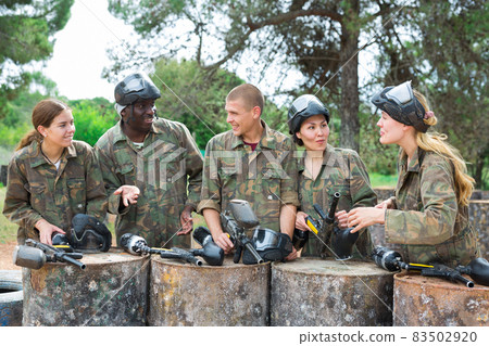 Smiling friends chatting after successful paintball match Smiling friends chatting after successful paintball match 83502920