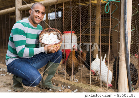 Smiling man holds a basket of chicken eggs in his hands. Smiling man holds a basket of chicken eggs in his hands. 83503195