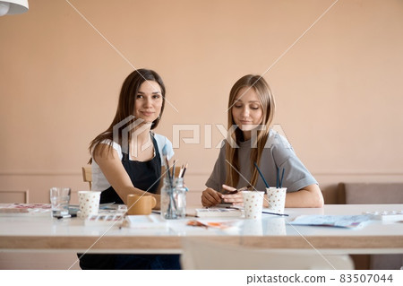 Front view of four beautiful caucasian female at art workshop. A young teacher teaches drawing 83507044