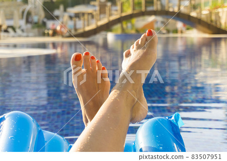 Feet of a woman on the swimming pool 83507951