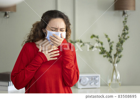 Young woman coughing in a medical mask 83508695