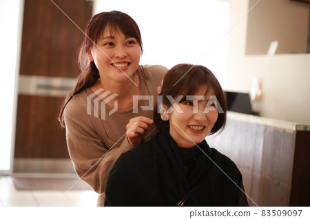 A beautician who puts a cover on the customer's ear A beautician who puts a cover on the customer's ear 83509097